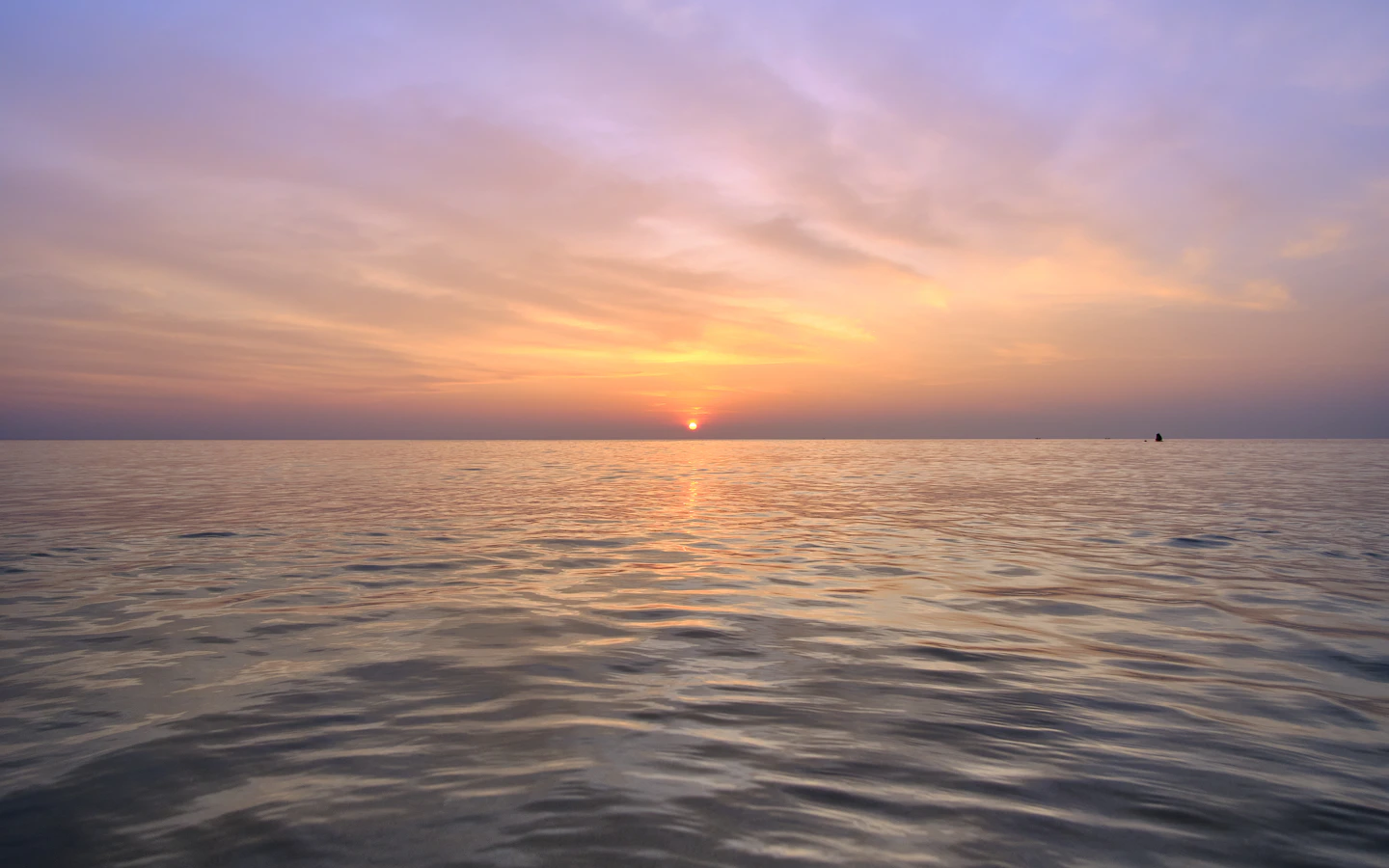 A quiet sea beneath a pink and peach sunset